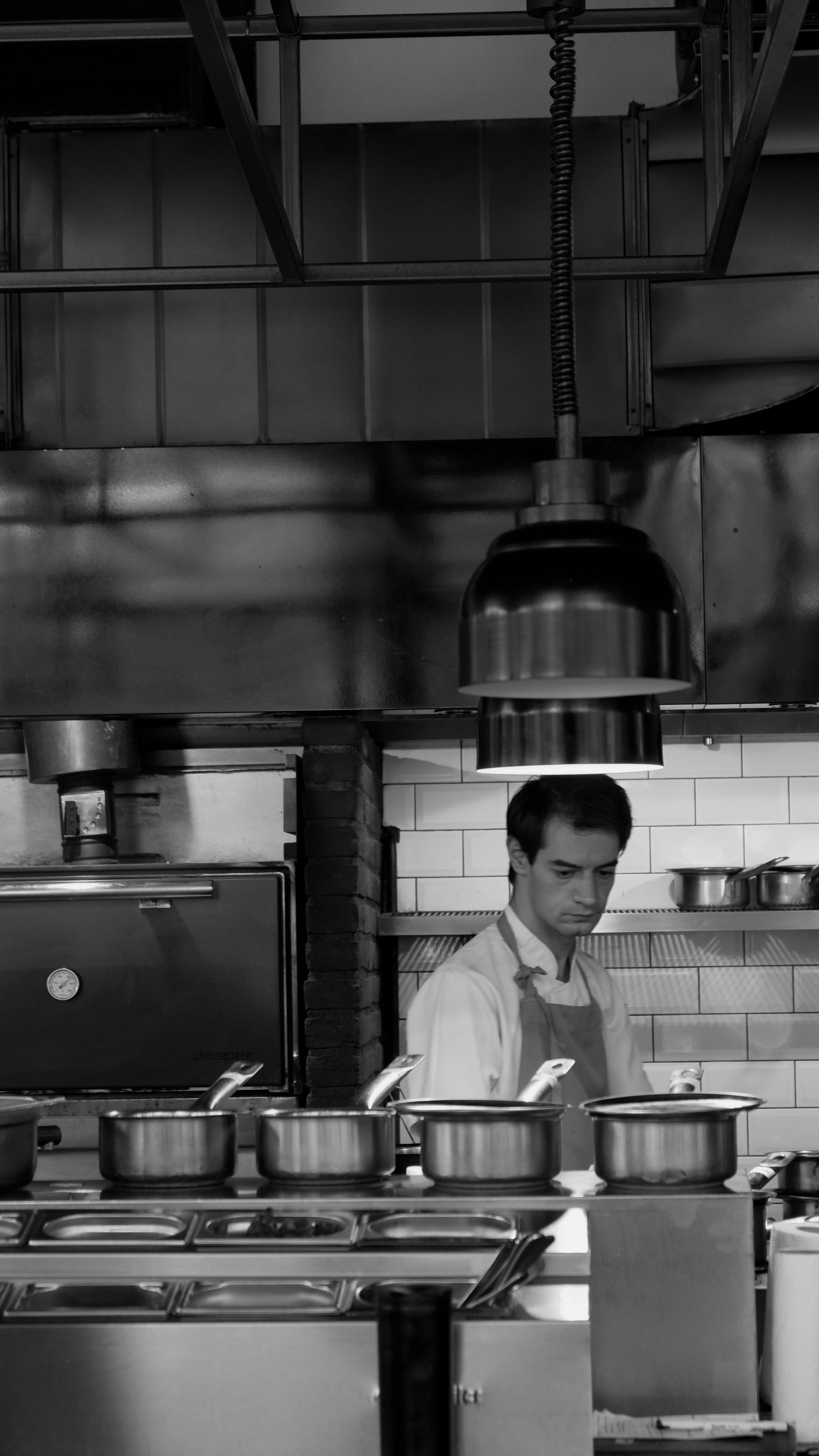 Chef working in a large industrial kitchen surrounded by stainless steel cookware